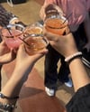Arms of a bunch of people cheering with their cups with juice in them.