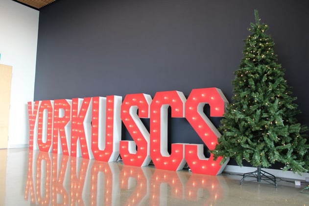 YorkU SCS red signage near a wall with a Christmas tree