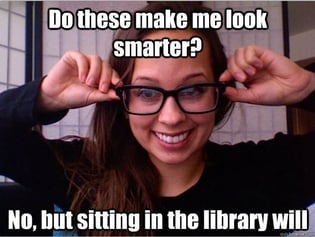 Lady holding her glasses with the caption that says 'Do these make me look smarter? No, But sitting in the library will'