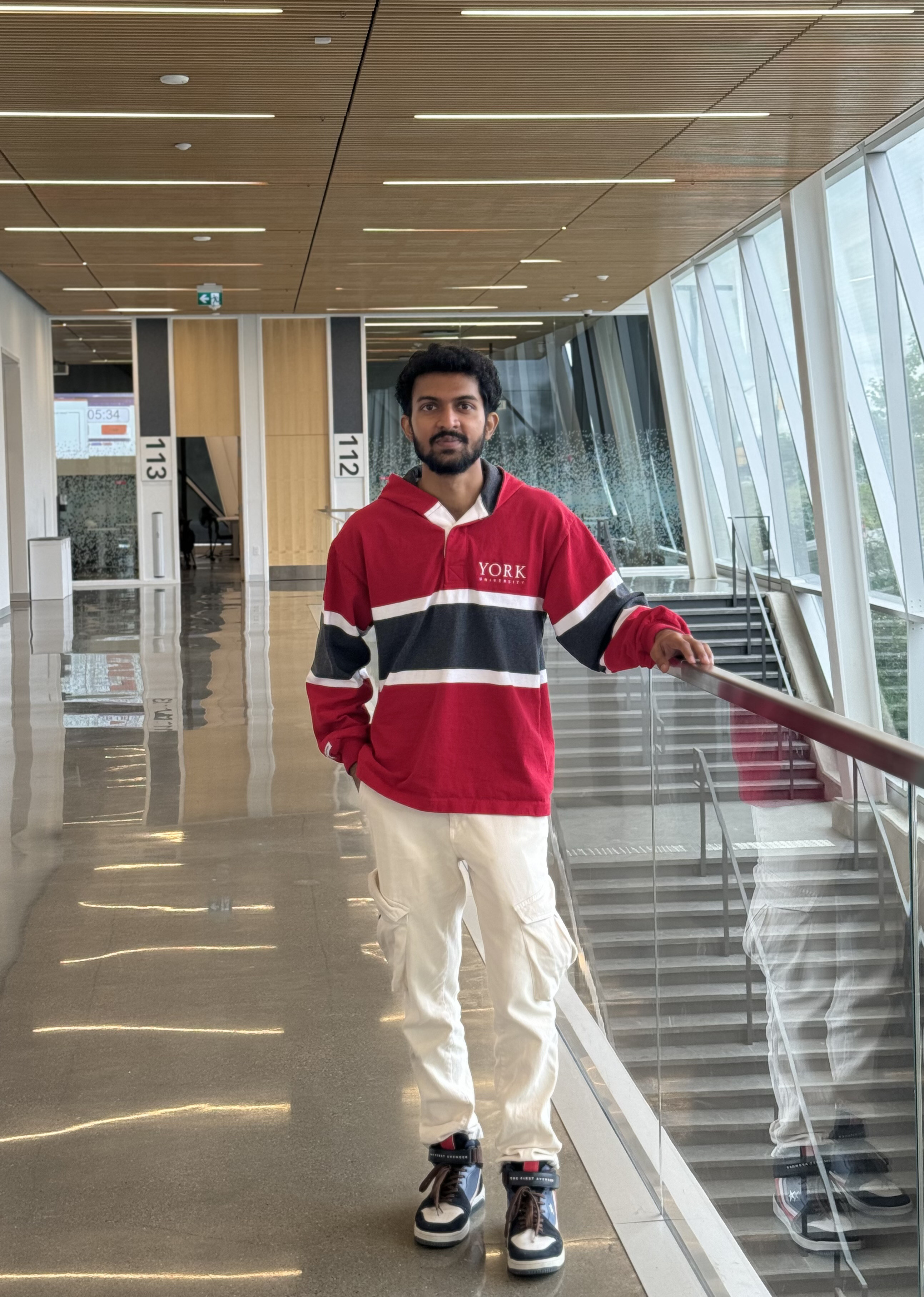 A man standing wearing york university named topwear inside a building
