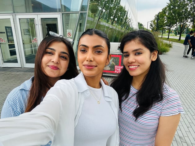 Three girls clicking a selfie near a building