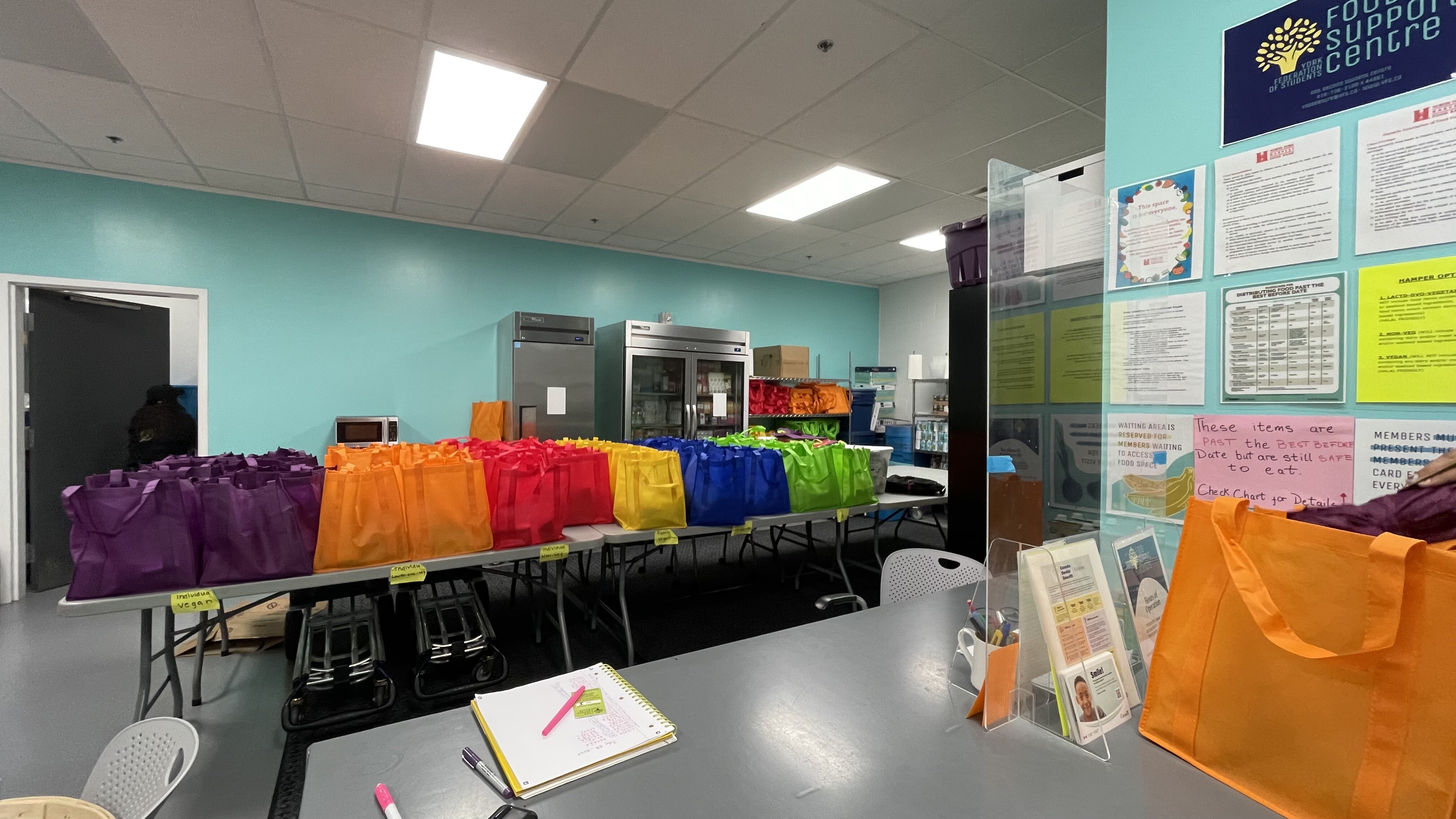 colorful bags at york university's food support centre with refrigerator in the back and storage space