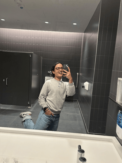 Boy smiling while taking a mirror selfie in the washroom.