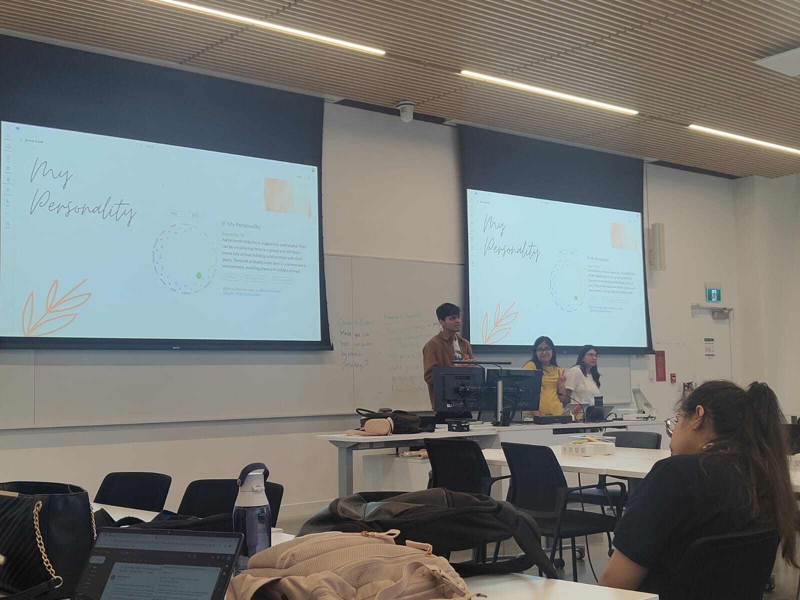 Me and my friends presenting about 'My Personality' in our class, standing at the front with our presentation shown on two large screens.