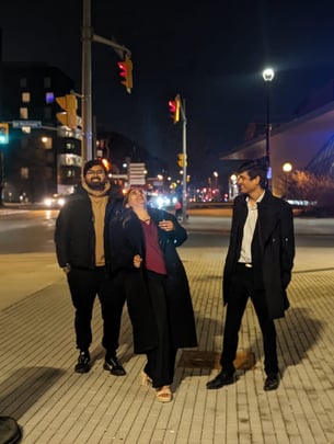 Three People (2 Male and 1 Female) having a candid laughter moment, with buildings and street light in background