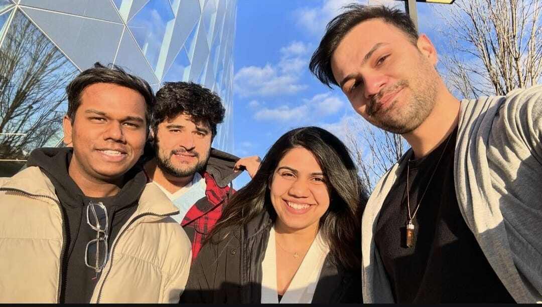 A group of friends squinting into the sun, pretending it’s warm while secretly freezing. The guy on the right is clearly thinking, 'Is it just me, or does this building make my jawline look even sharper?