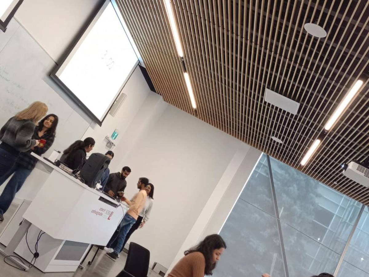 York University Students in the class siting at their table. In the frame there is big glass window through which you can see the outside view