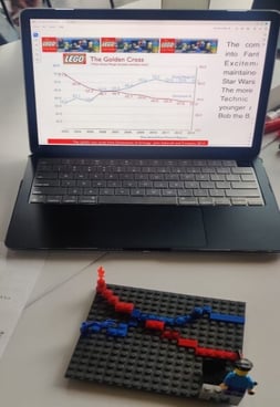 Golden cross made from LEGO pieces displayed next to a MacBook showing a picture of the same cross