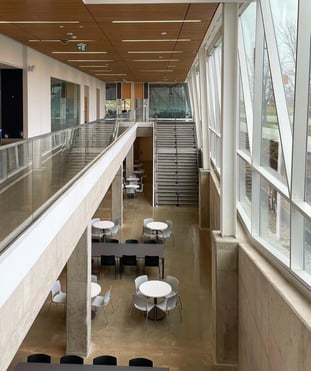 Interior of York University School of Continuing Studies with lavish and modern design, featuring glass walls, railings, a staircase, and seating arrangement including long table and chairs