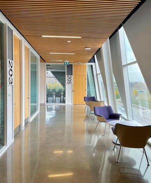  Interior of the building with classroom number 205, left to it is classroom number 203 and in front are some seats with angular glass windows 