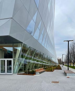 York University School of Continuing Studies building, featuring modern and angular architecture with outdoor benches and street lights on the side in daylight condition