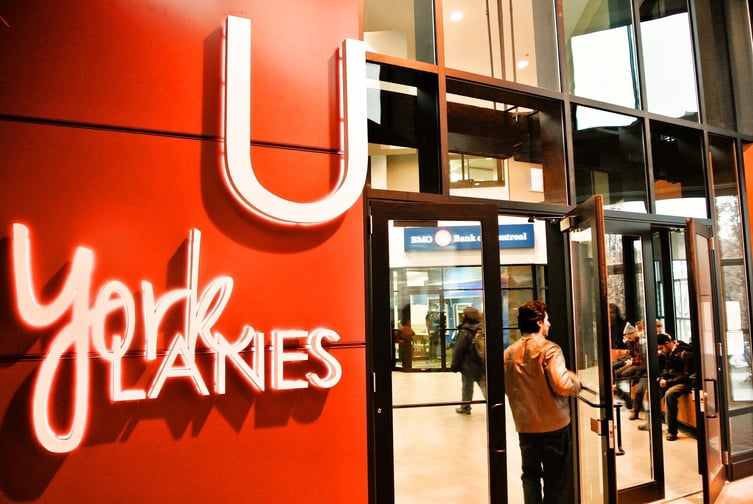 Entrance to York Lanes at York University with a neon sign and people inside near a BMO branch.