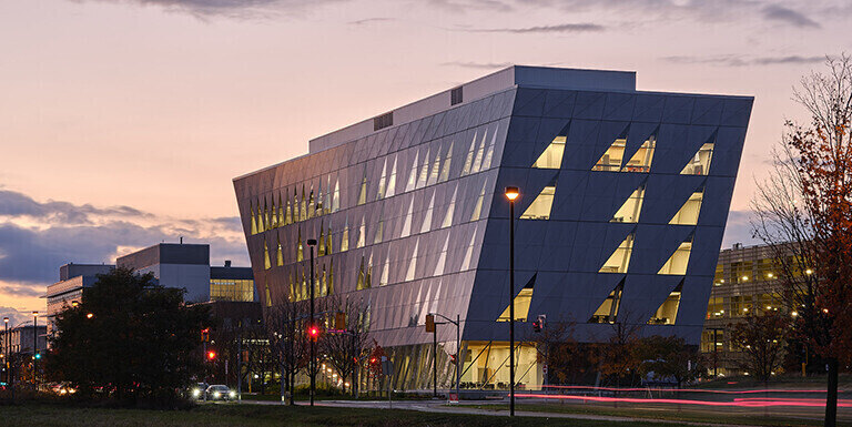 York University school of continuing studies building with few other building in the background of the image with few cars on the road and trees in the image